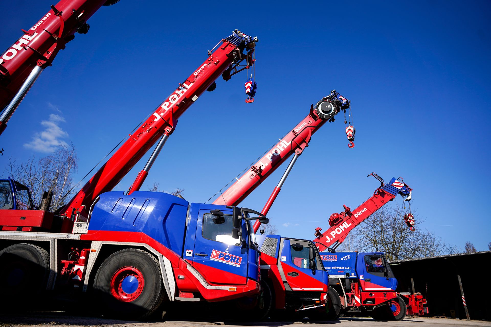 Ein rot-blauer Kranwagen steht neben einem anderen Kranwagen.