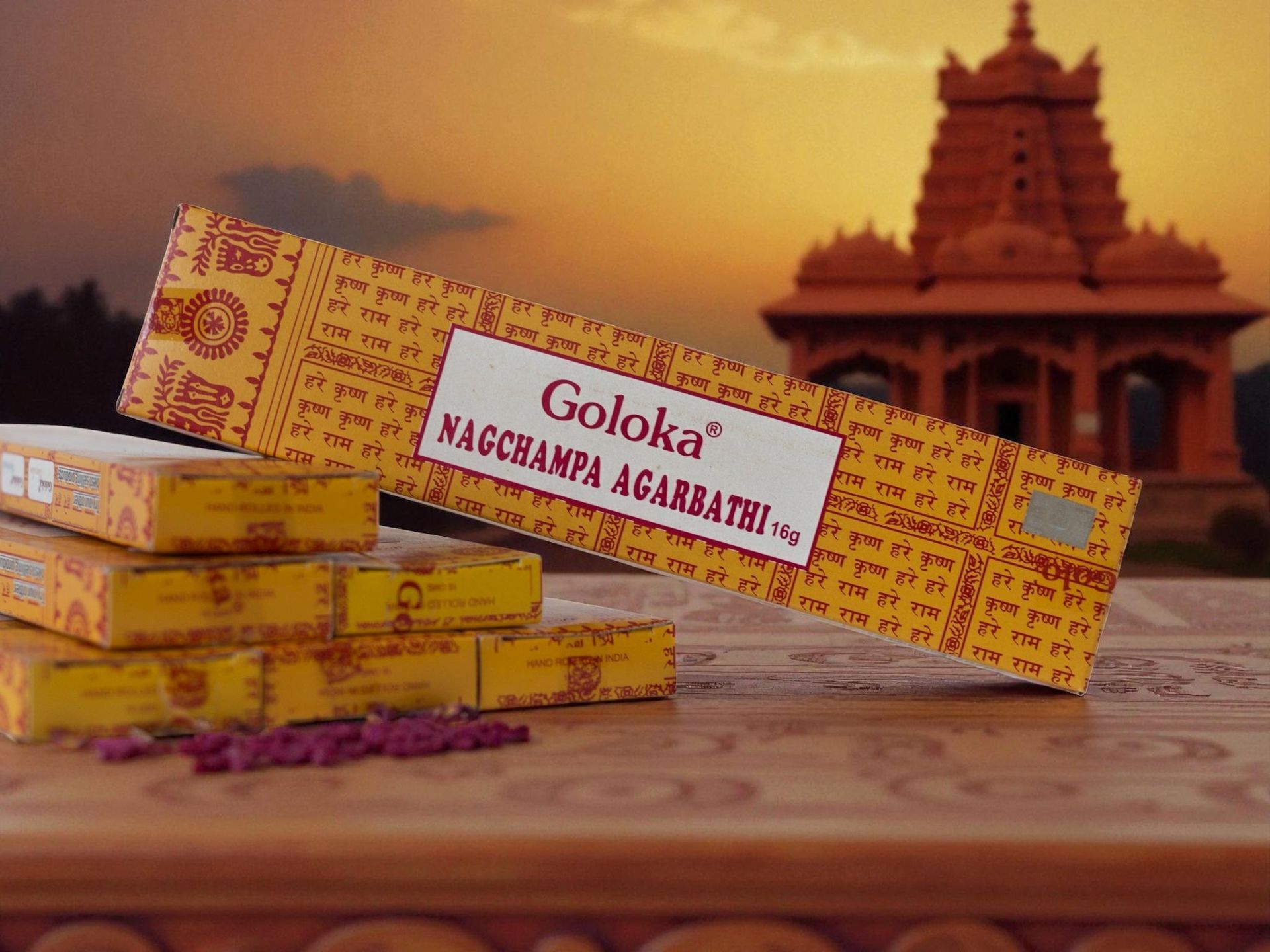 Cajas de incienso agarbathi Goloka Nagchampa, con templo y puesta de sol al fondo.