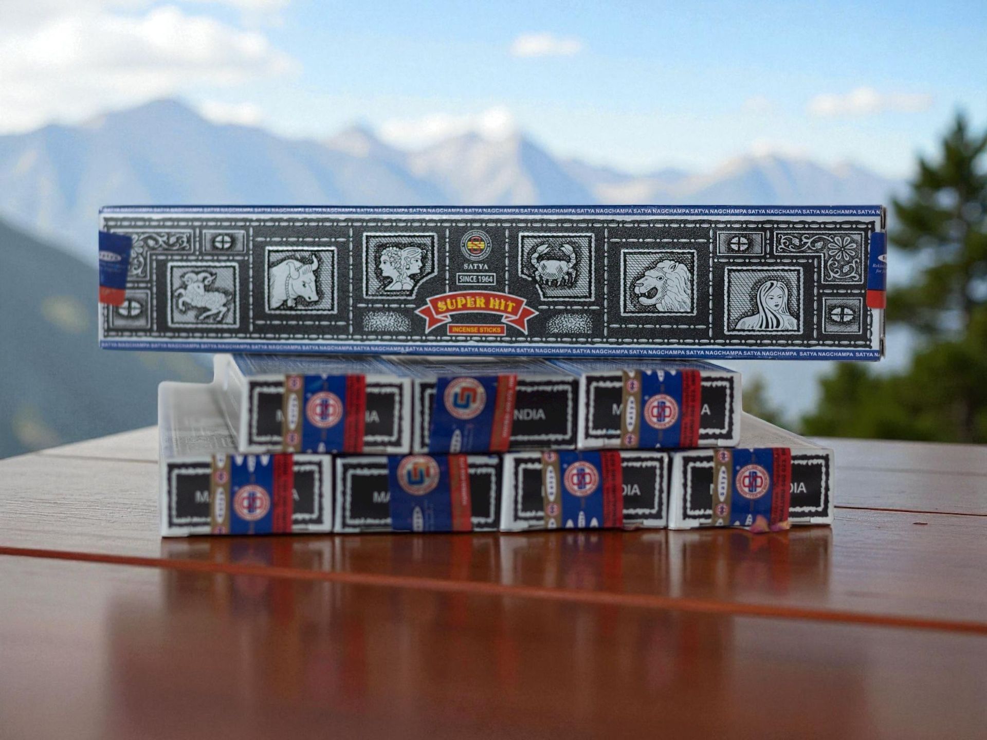 Cajas de incienso con fondo de montañas. Las cajas de incienso son azules, blancas y rojas sobre una superficie de madera.