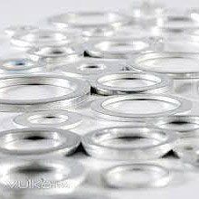 Arandelas de sellado de metal plateado, de muchos tamaños, esparcidas sobre una superficie.