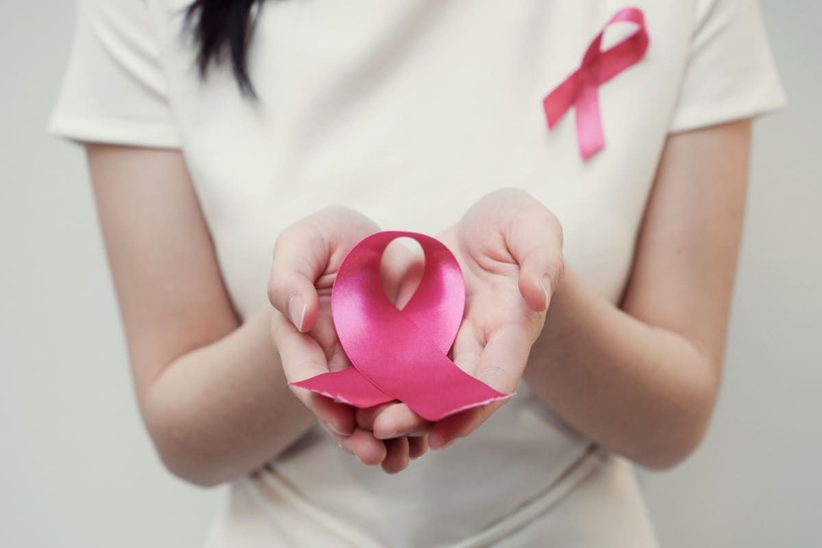 Una mujer sostiene una cinta rosa en sus manos.