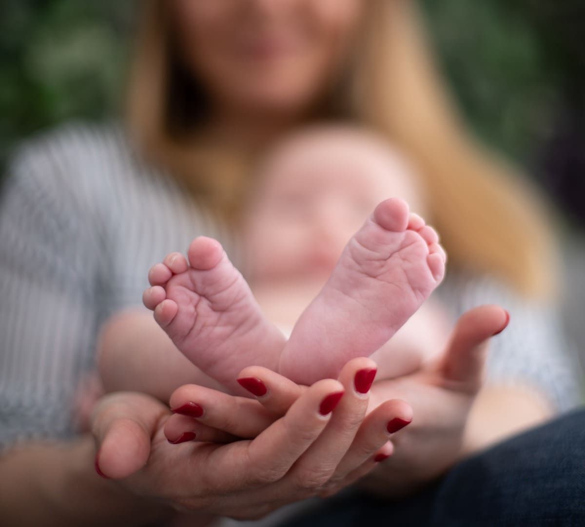 Una mujer sostiene los pies de un bebé en sus manos.