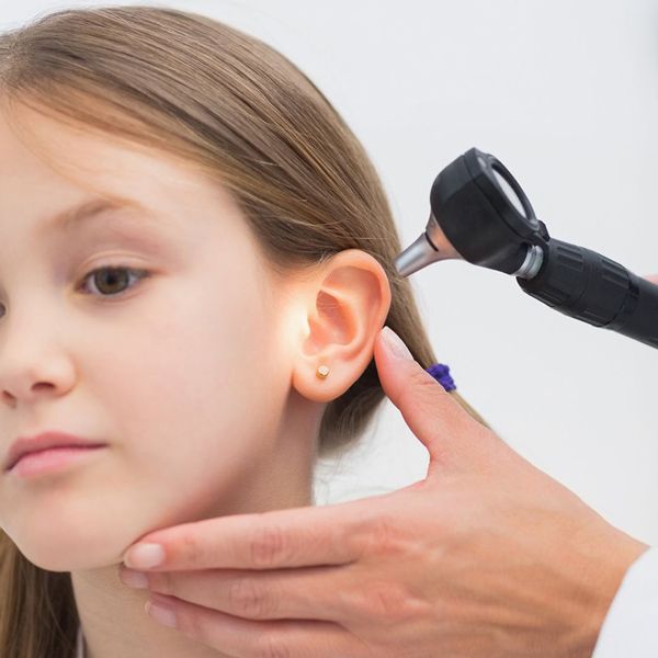 Médico examina el oído de una niña con un otoscopio en un entorno clínico.