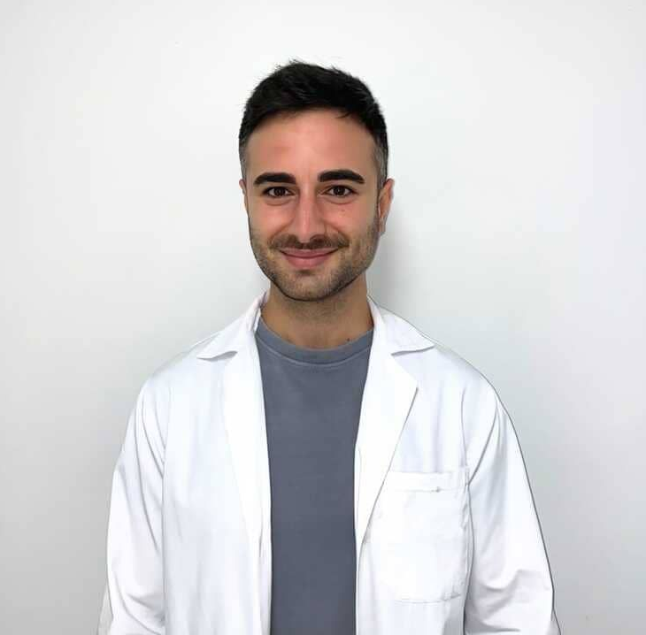 Un hombre con traje y camisa blanca sonríe a la cámara.