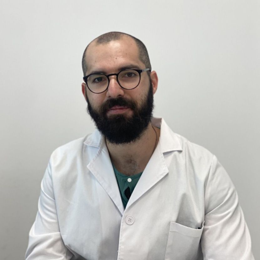 Un hombre con traje y camisa blanca sonríe a la cámara.