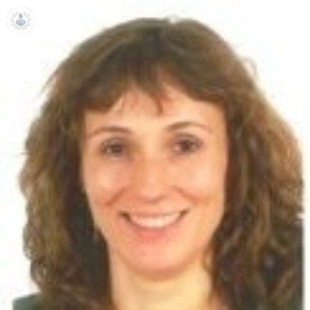 Una mujer con cabello rizado está sonriendo para la cámara.
