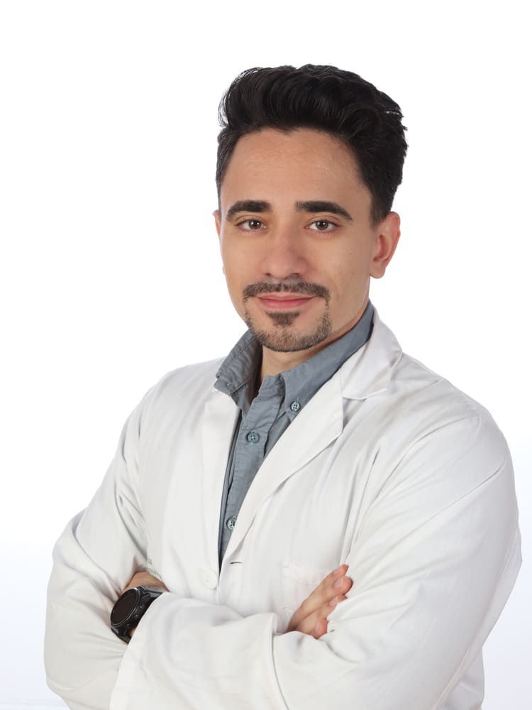 Un hombre con traje y camisa blanca sonríe a la cámara.