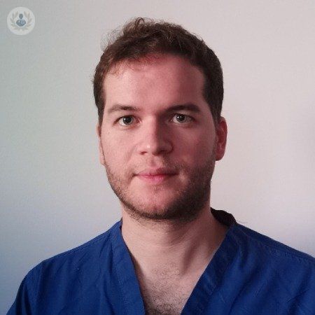 Un hombre con barba lleva una blusa azul.