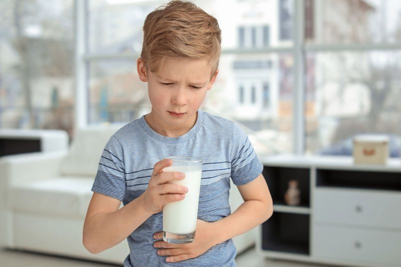 Un niño pequeño sostiene un vaso de leche en su mano.