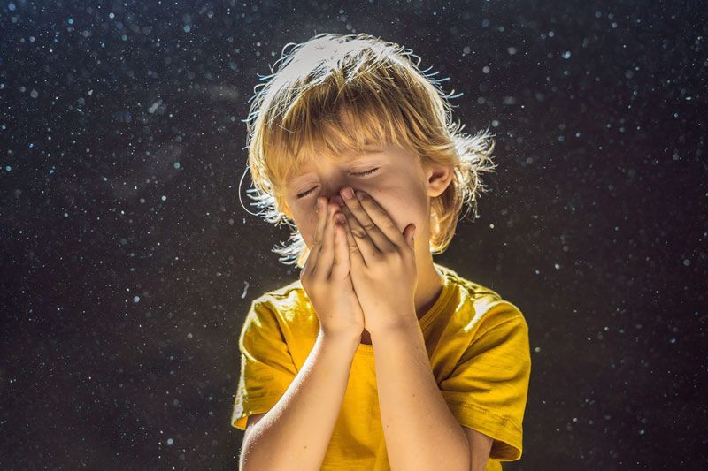 Un niño con una camisa amarilla se suena la nariz