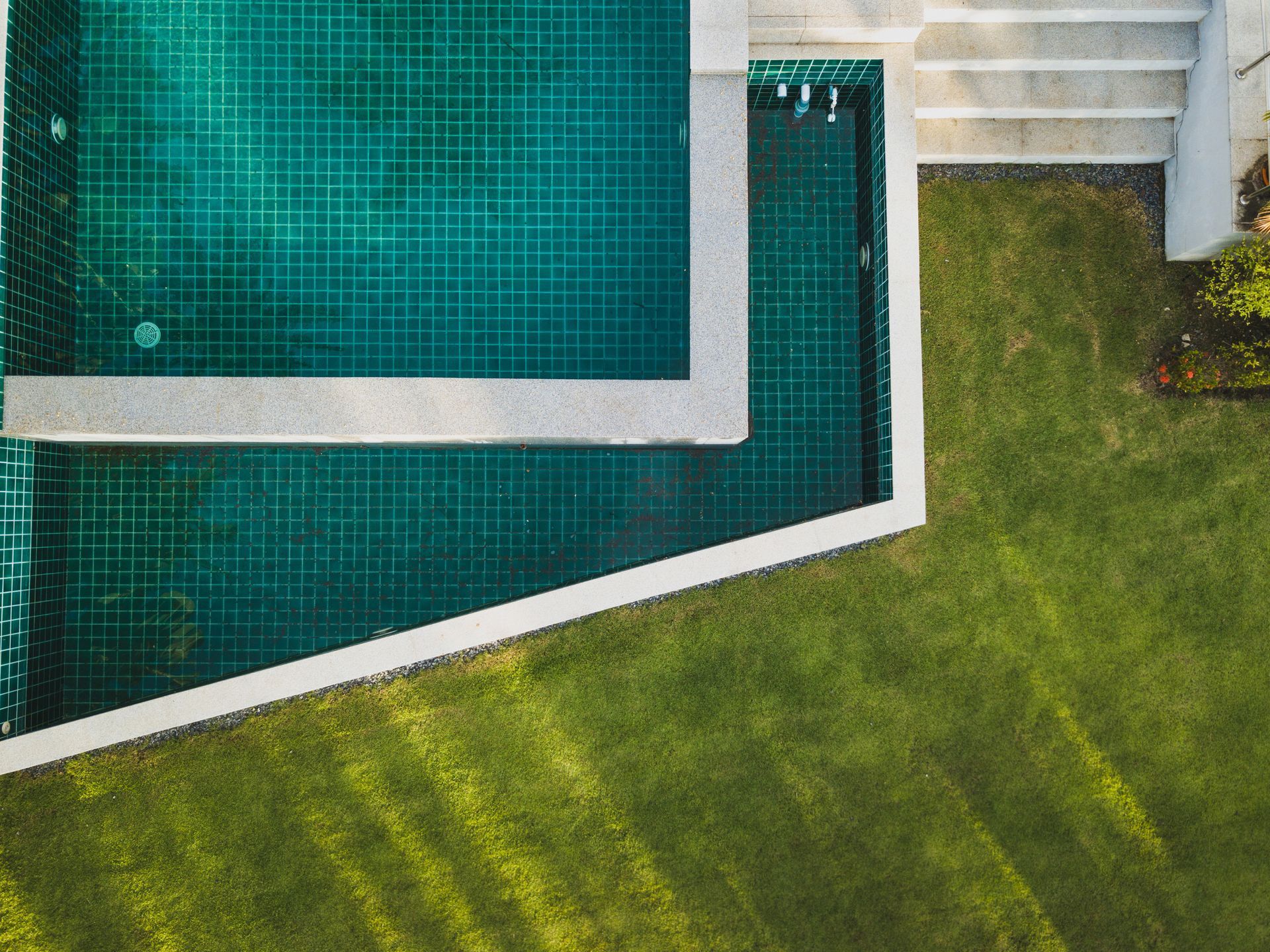 Una vista aérea de una gran piscina rodeada de césped verde.