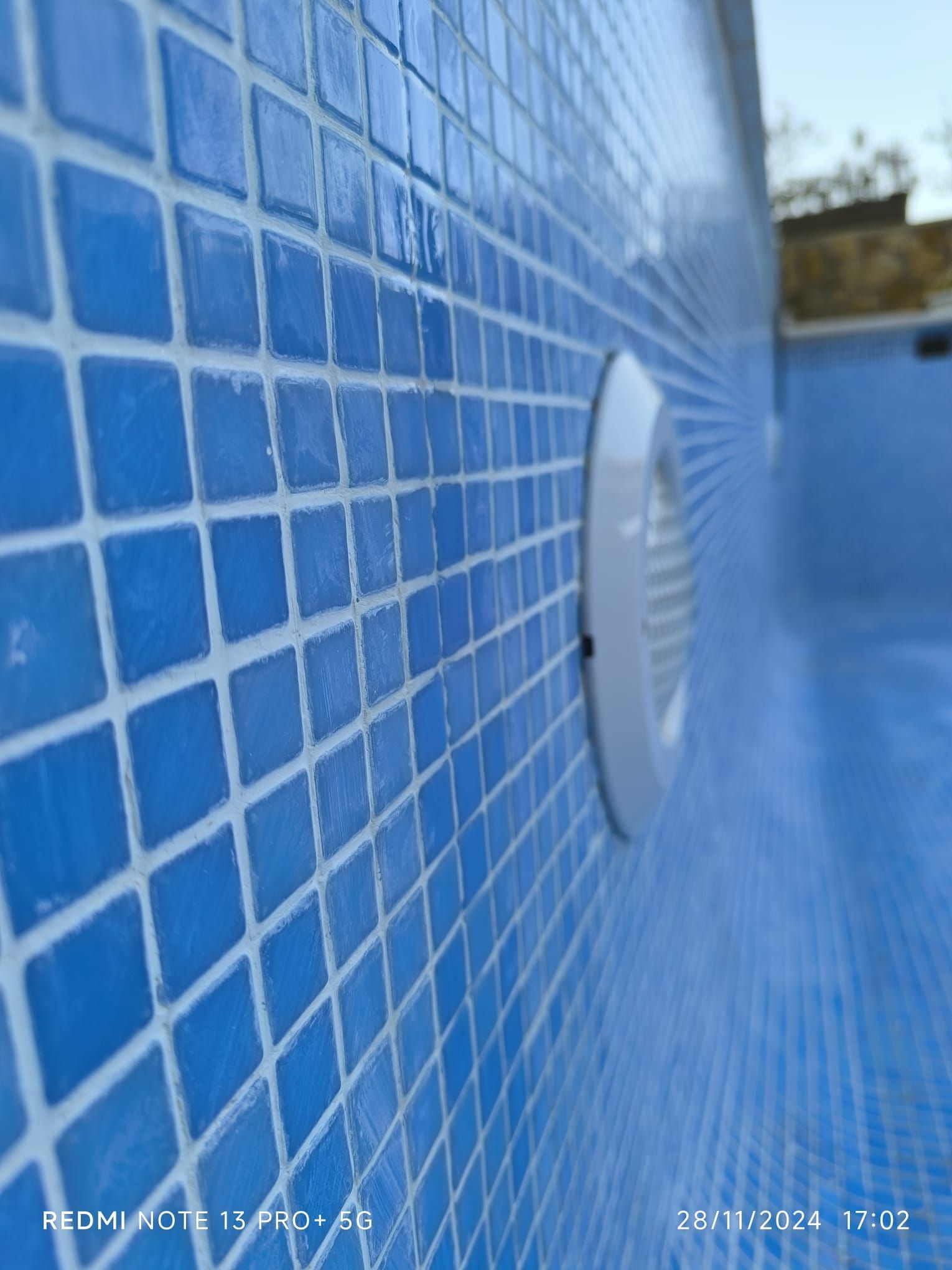 Un primer plano de una pared de azulejos azules en una piscina.