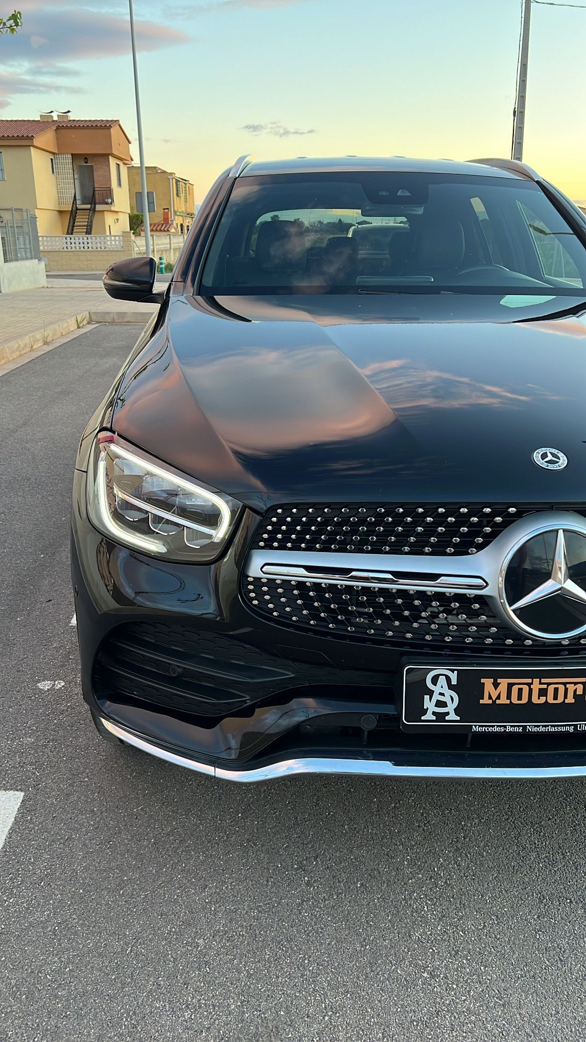 SUV Mercedes-Benz negro estacionado en la carretera, vista frontal. Colores del atardecer en el cielo.