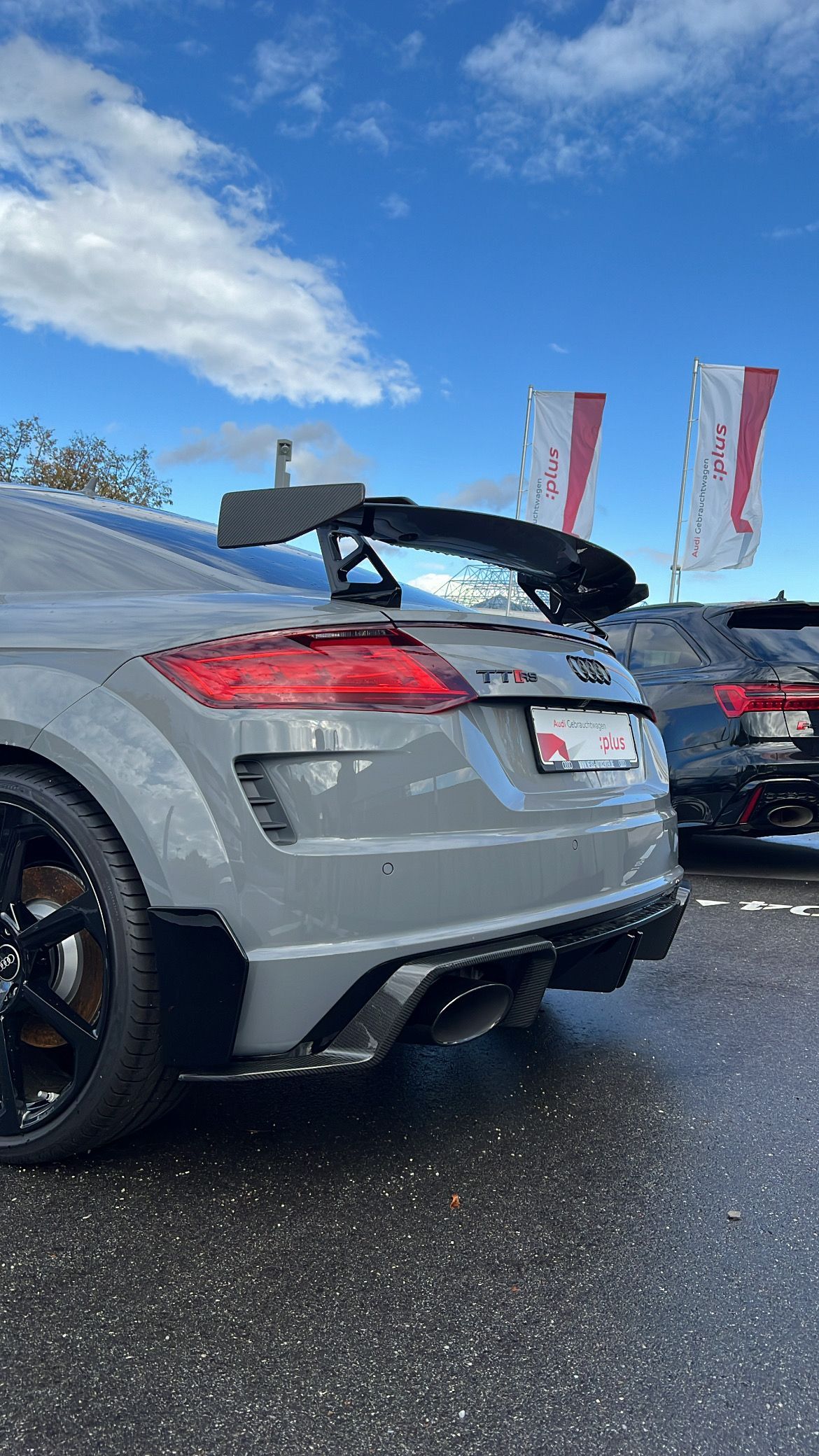 Audi TT RS coupé gris con un gran alerón estacionado al aire libre.