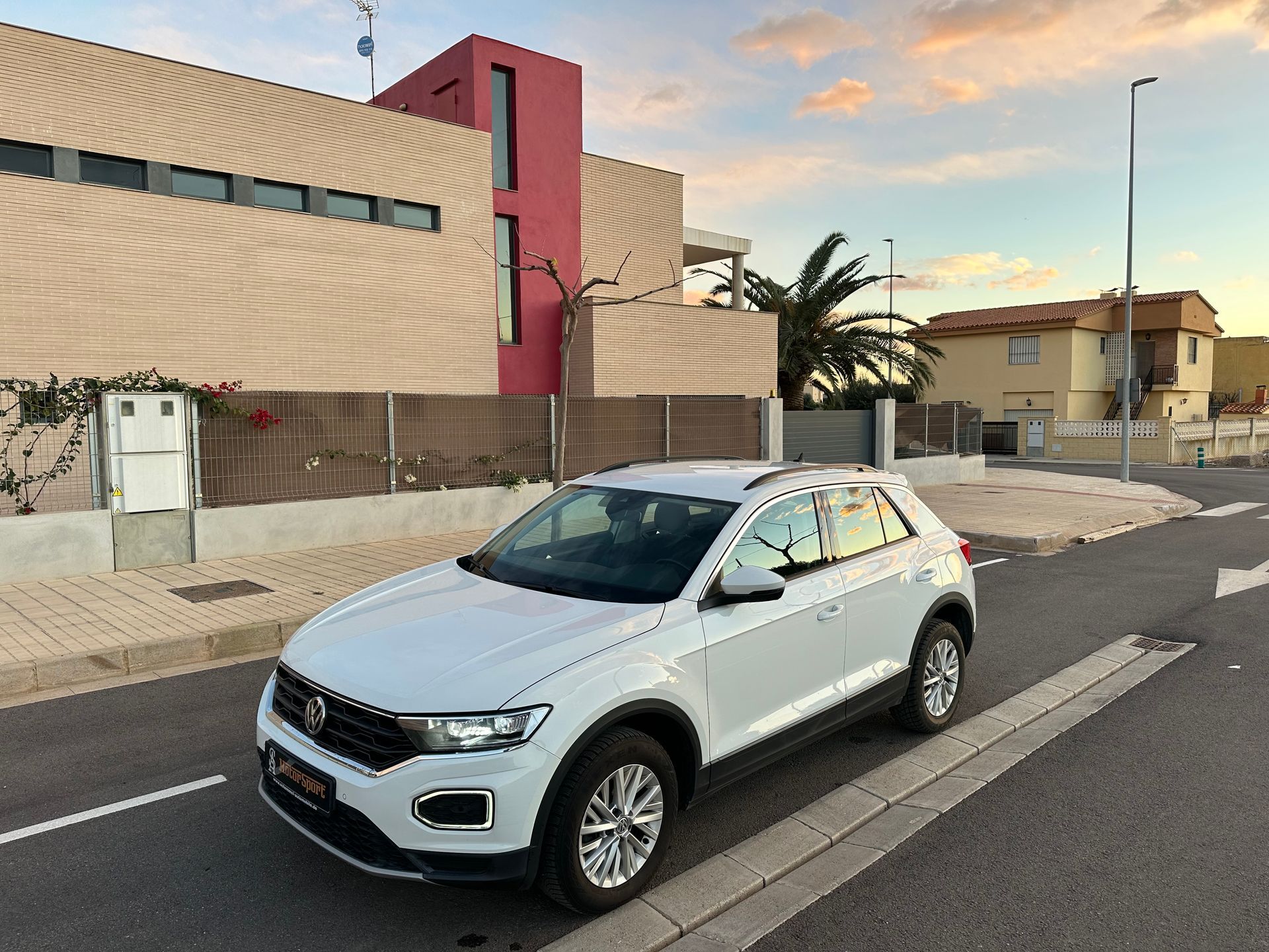 Volkswagen T-Roc blanco estacionado en una calle frente a una casa moderna.