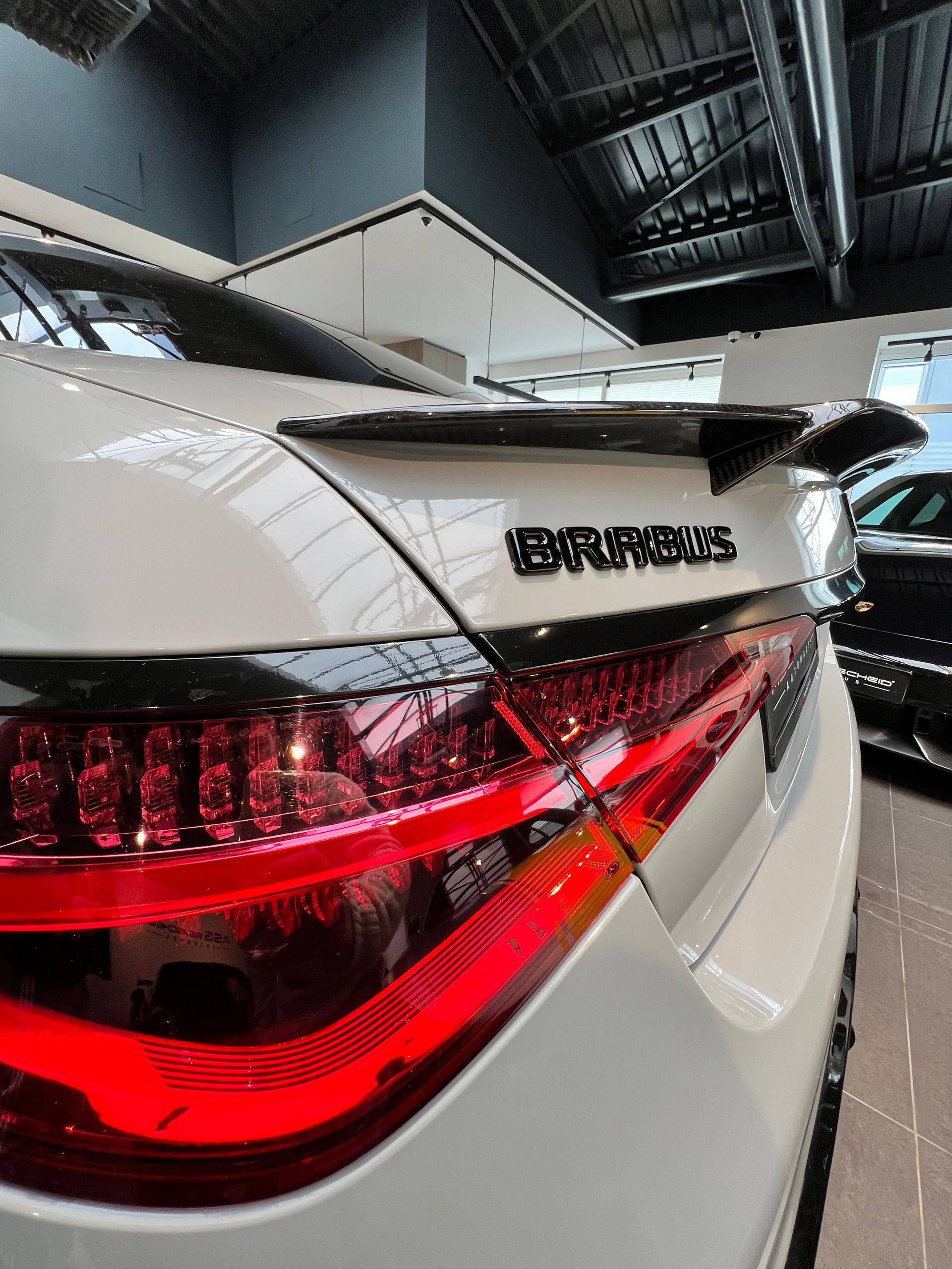 Un Audi sedán plateado estacionado en una calle frente a un moderno edificio de color beige y rojo.
