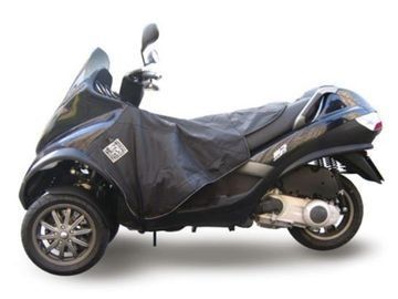 Un scooter negro de tres ruedas con una cubierta está estacionado sobre un fondo blanco.