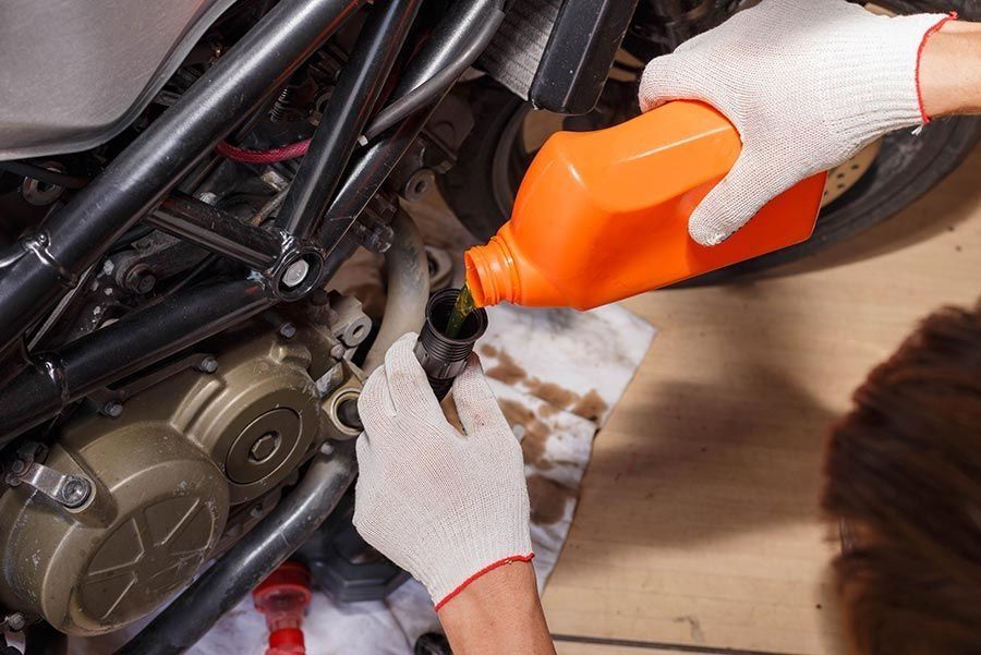 Una persona está vertiendo aceite en el motor de una motocicleta.