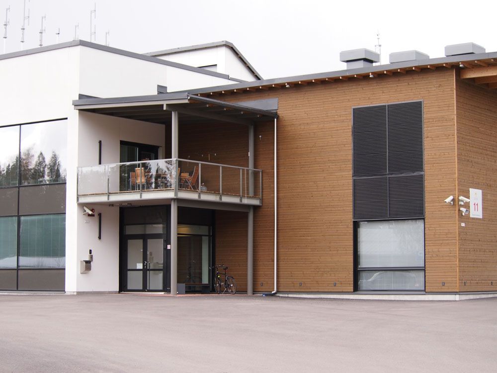 Moderni rakennus, jossa on ruskea puinen julkisivu, parveke ja suuri tumma ikkuna.