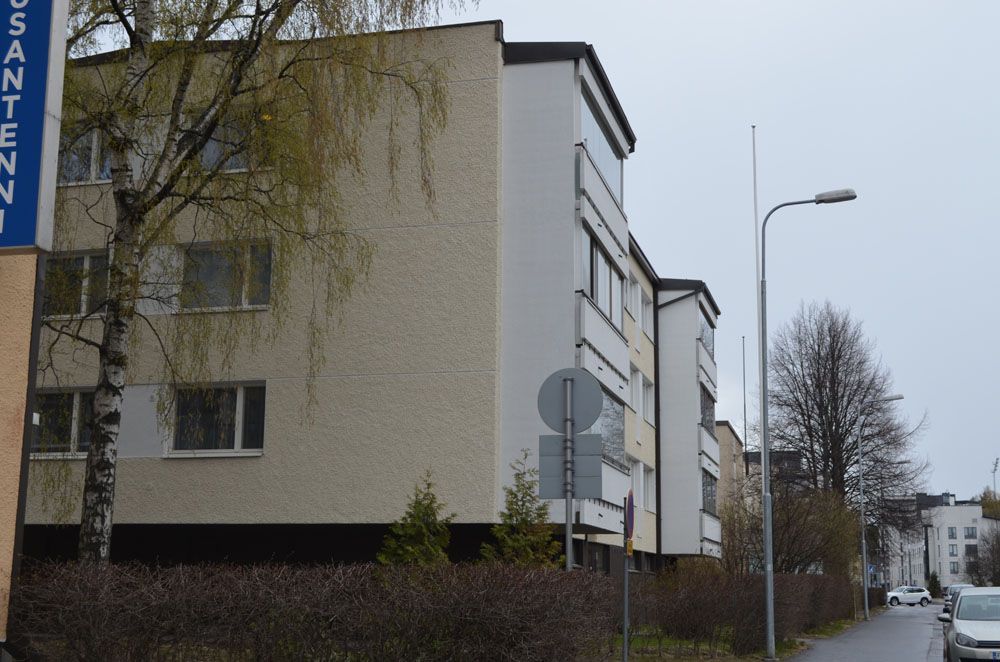 Kerrostaloja, joissa on valkoiset seinät ja tummat katot pilvisenä päivänä.