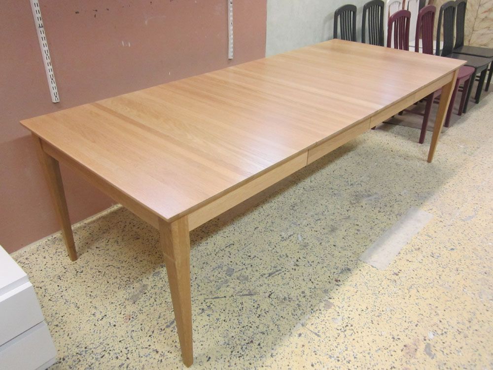 Vaalea puinen ruokapöytä viistot jalat kuviollisella lattialla.