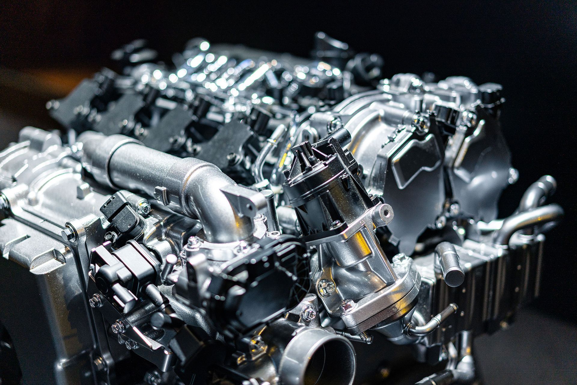 Nahaufnahme eines silbernen Automotors mit verschiedenen metallischen Bauteilen, die filigrane mechanische Details zeigt.