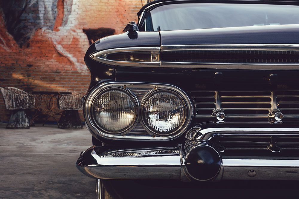 Nahaufnahme der Frontpartie eines klassischen schwarzen Autos mit Chromakzenten und Doppelscheinwerfern.