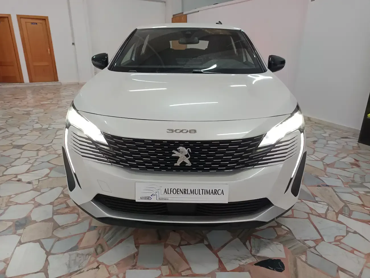 Un coche blanco está aparcado en una habitación con suelo de baldosas.