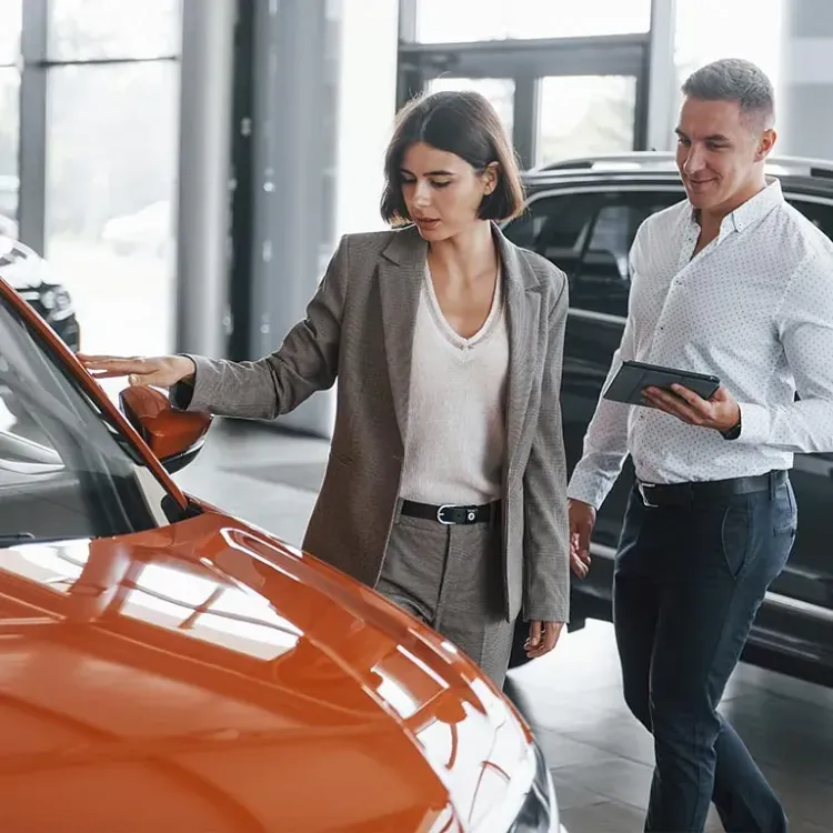 Un hombre y una mujer miran un coche en una sala de exposición.