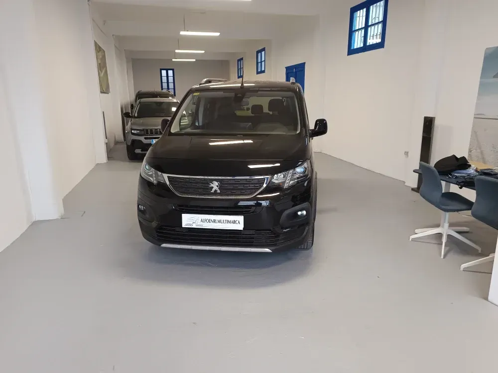 Un coche negro está aparcado en una sala de exposición con otros coches.