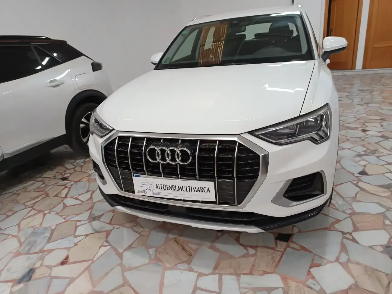 Un Audi Q3 blanco está aparcado en un garaje.