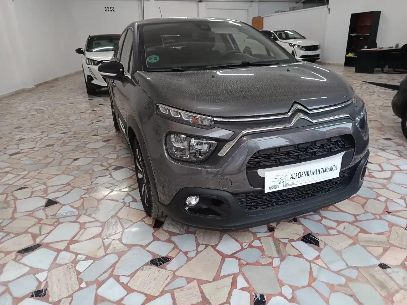 Un Citroën C3 gris está estacionado en una sala de exposición.