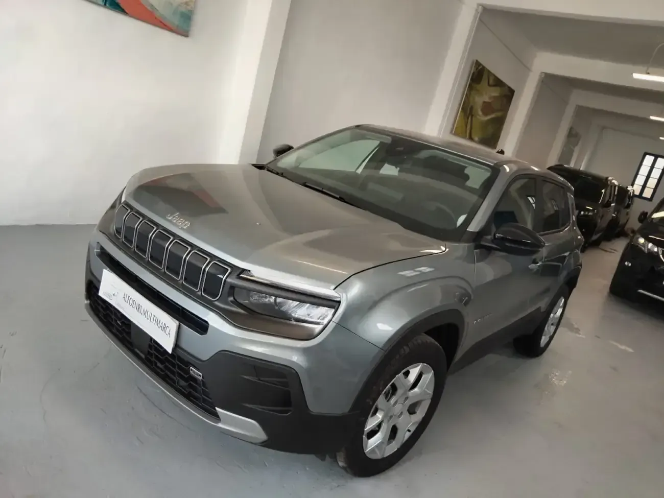 Un Jeep Compass gris está estacionado en una sala de exposición.