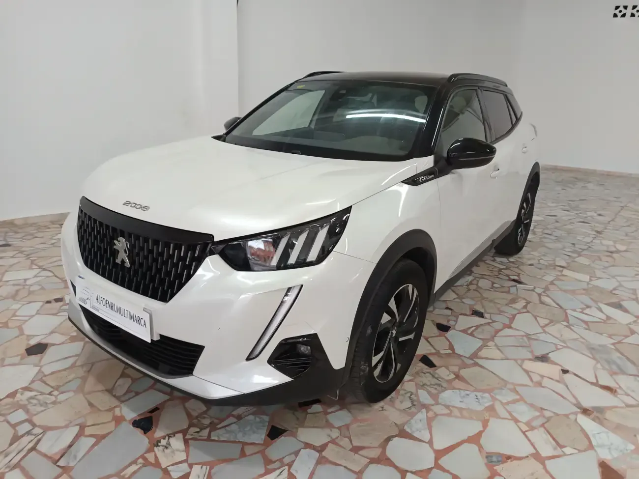 Un coche blanco está aparcado en una habitación con suelo de baldosas.