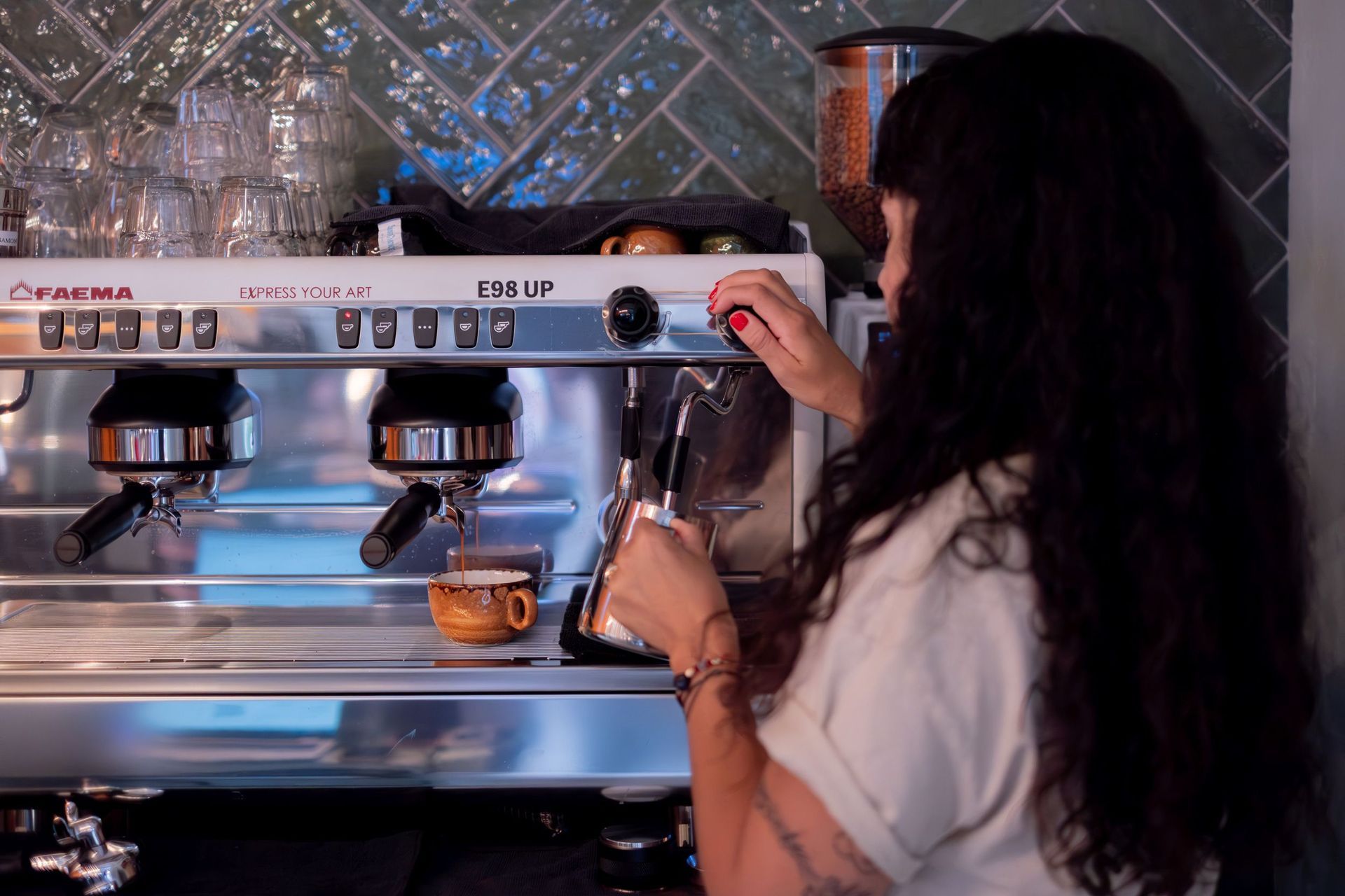 Person using an espresso machine in a kitchen, placing a cup under the portafilter.