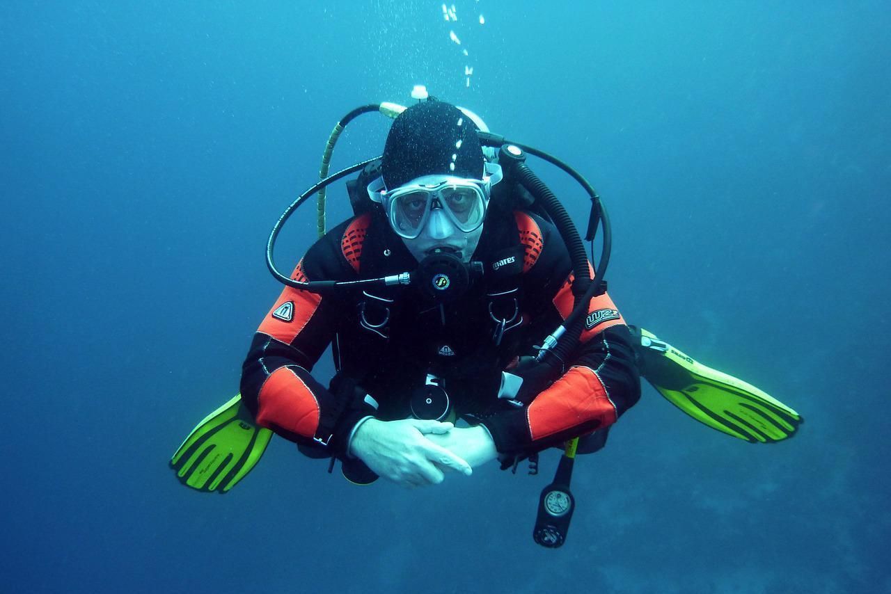 Scuba diver in red-and-black gear with green fins swimming underwater