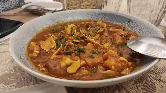 Un tazón de sopa con una cuchara dentro sobre una mesa.
