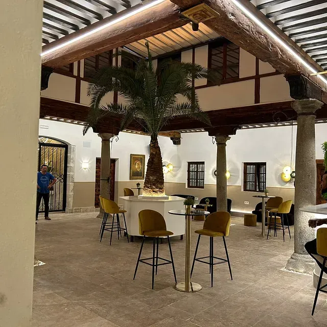 Una gran sala con mesas y sillas y una palmera en el medio.