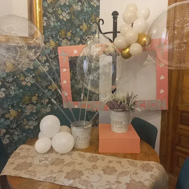 Una mesa con globos y un jarrón que dice 'te amo'