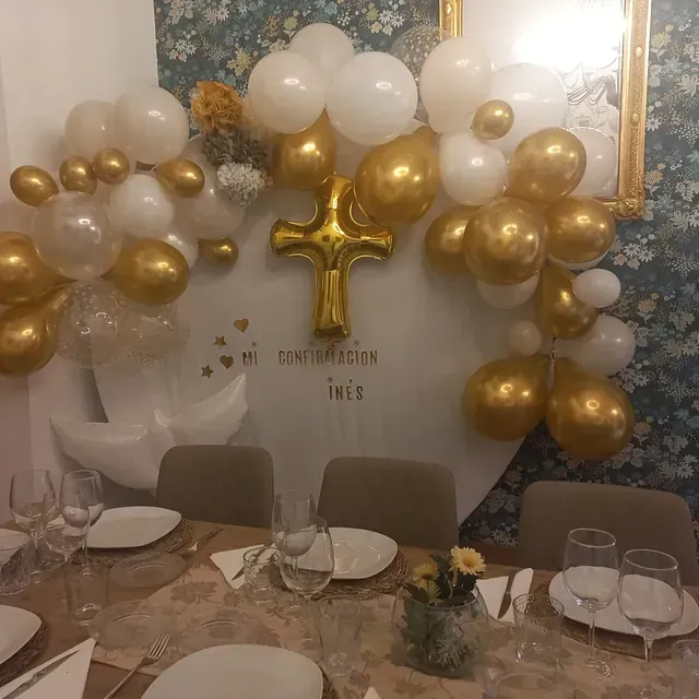 Una mesa con platos y vasos y globos encima.