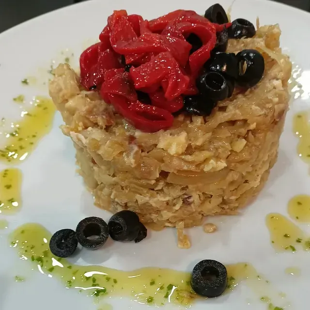 Un plato de comida con aceitunas y pimientos encima.