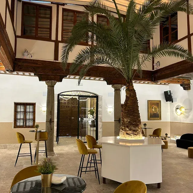 Una habitación con mesas y sillas y una palmera en el medio.
