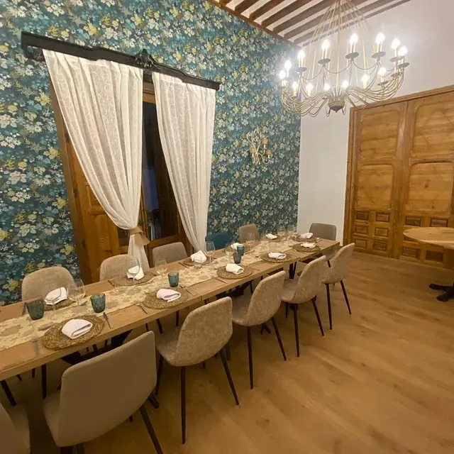 Un comedor con una mesa larga y sillas y una lámpara de araña.