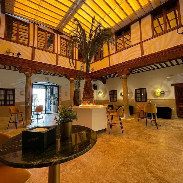 Una gran sala con mesas y sillas y una palmera en el medio.