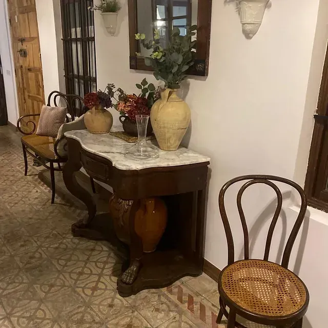 Un pasillo con una mesa, sillas y jarrones.