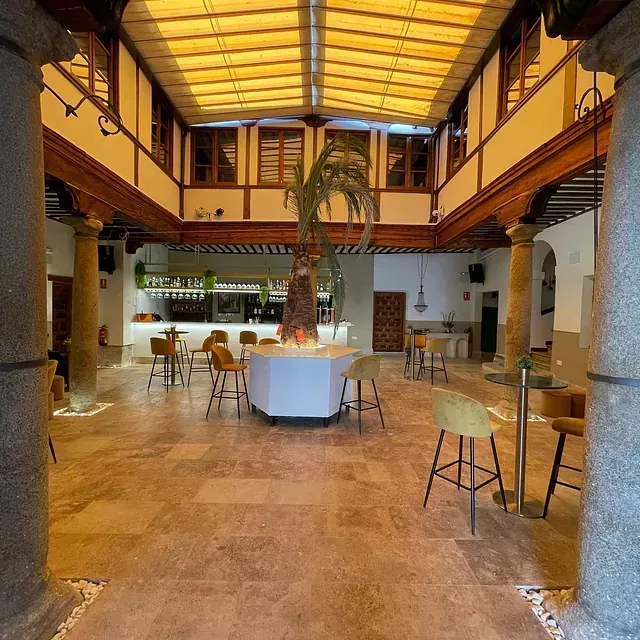 Una gran sala con mesas y sillas y una palmera en el medio.