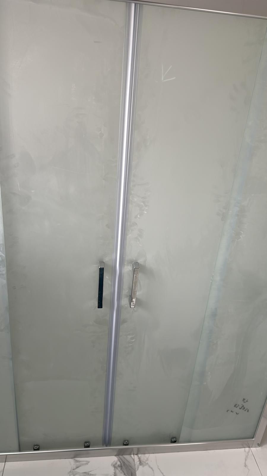 Eine Person installiert eine graue Terrassenüberdachung auf einem zweistöckigen Gebäude mit Balkon und blauen Fensterläden.