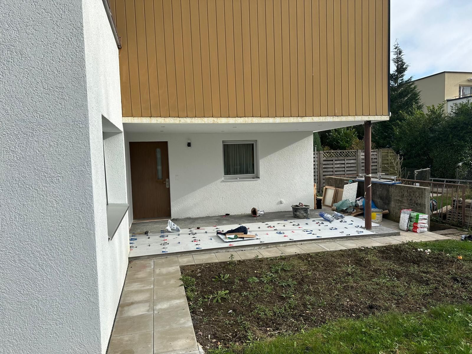 Außenansicht eines Hauses mit einem oberen Stockwerk aus braunem Holz und einem unteren Stockwerk aus weißem Stuck.