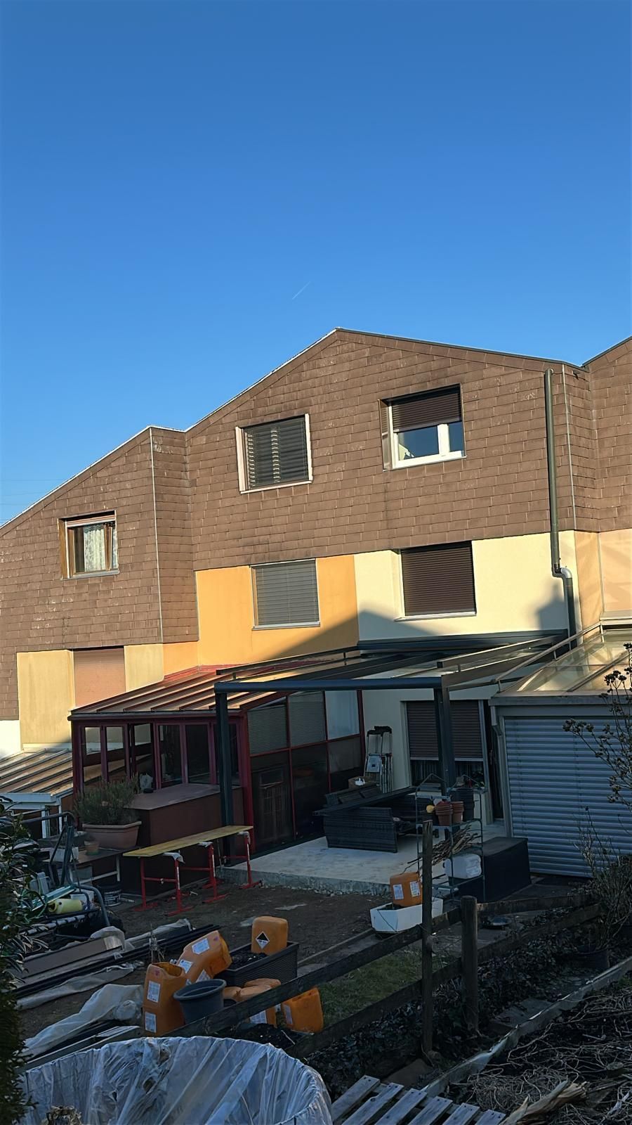 Blick auf den Hinterhof mit mehrstöckigen Gebäuden aus Backstein & Fassaden. Darunter befindet sich eine Terrasse mit Möbeln.