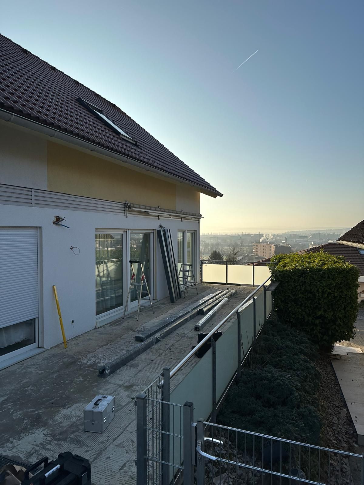 Baustelle mit einem teilweise fertiggestellten Gebäude. Das Haus hat Wände, ein Dach und eine Glasbarriere.